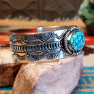 Sterling silver cuff bracelet with Kingman turquoise set in the oval bezel, framed by twisted rope, dotted accents, and stamped designs on the band.