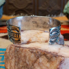 Sterling silver cuff bracelet with Kingman turquoise set in the oval bezel, framed by twisted rope, dotted accents, and stamped designs on the band.