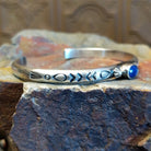 Sterling silver cuff bracelet with intricate stamping along the band and lapis set in the round bezel.