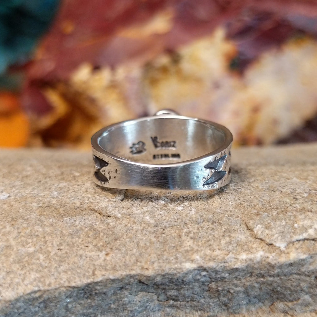 The ring's band features a textured finish with stamp details.