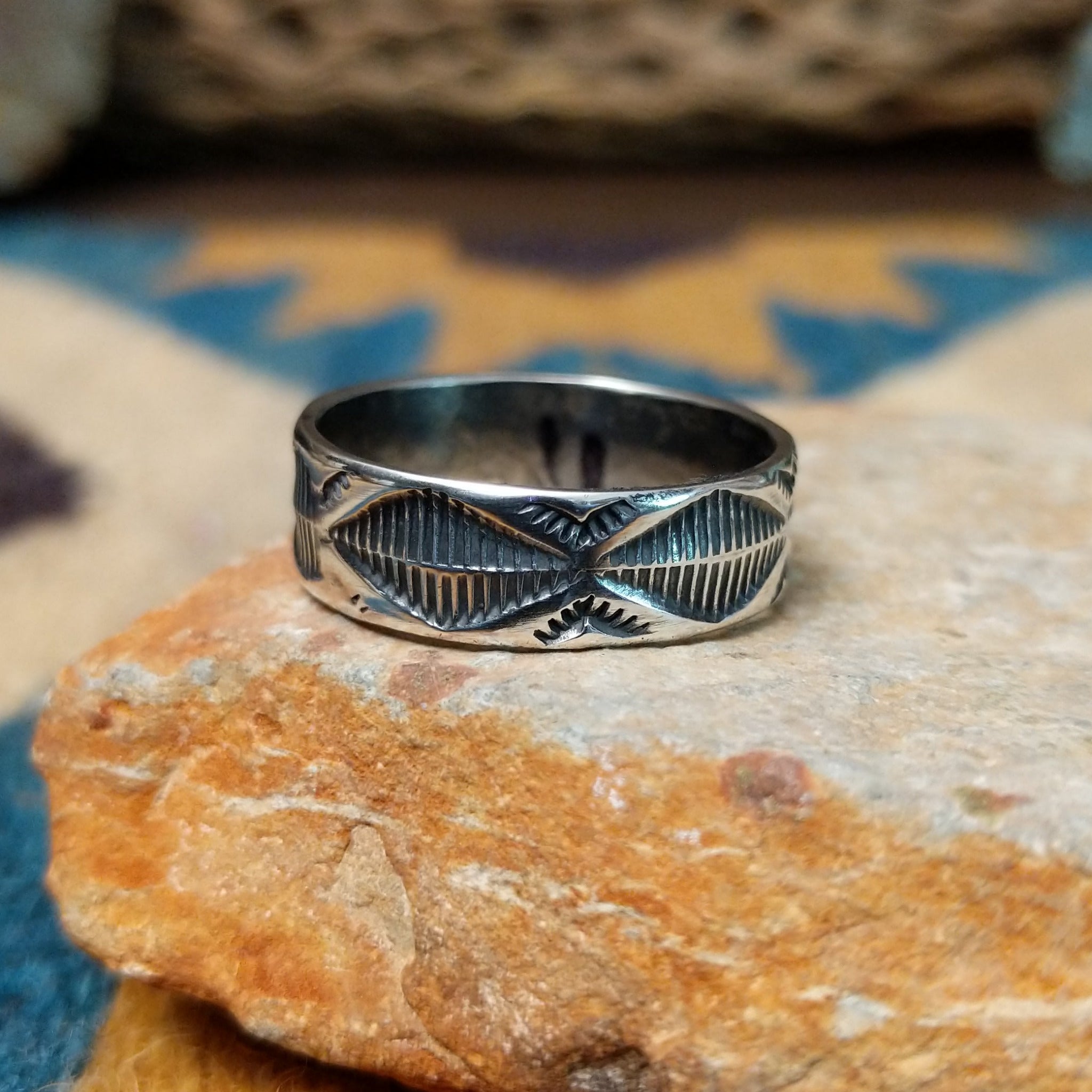 Handcrafted Navajo sterling silver stamped ring by Travis Teller featuring a wide band with deep traditional geometric stampwork and an oxidized finish.