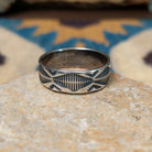 Handcrafted Navajo sterling silver stamped ring by Travis Teller featuring a wide band with deep traditional geometric stampwork and an oxidized finish.