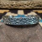 Stamped sterling silver cuff by B. Shorty, featuring intricate hand-stamped geometric and floral-inspired patterns on a handcrafted open sterling silver cuff.