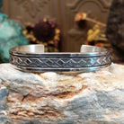 Sterling silver cuff bracelet with geometric stamped details and polished borders.