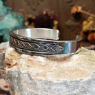 Sterling silver cuff bracelet with geometric stamped details and polished borders.