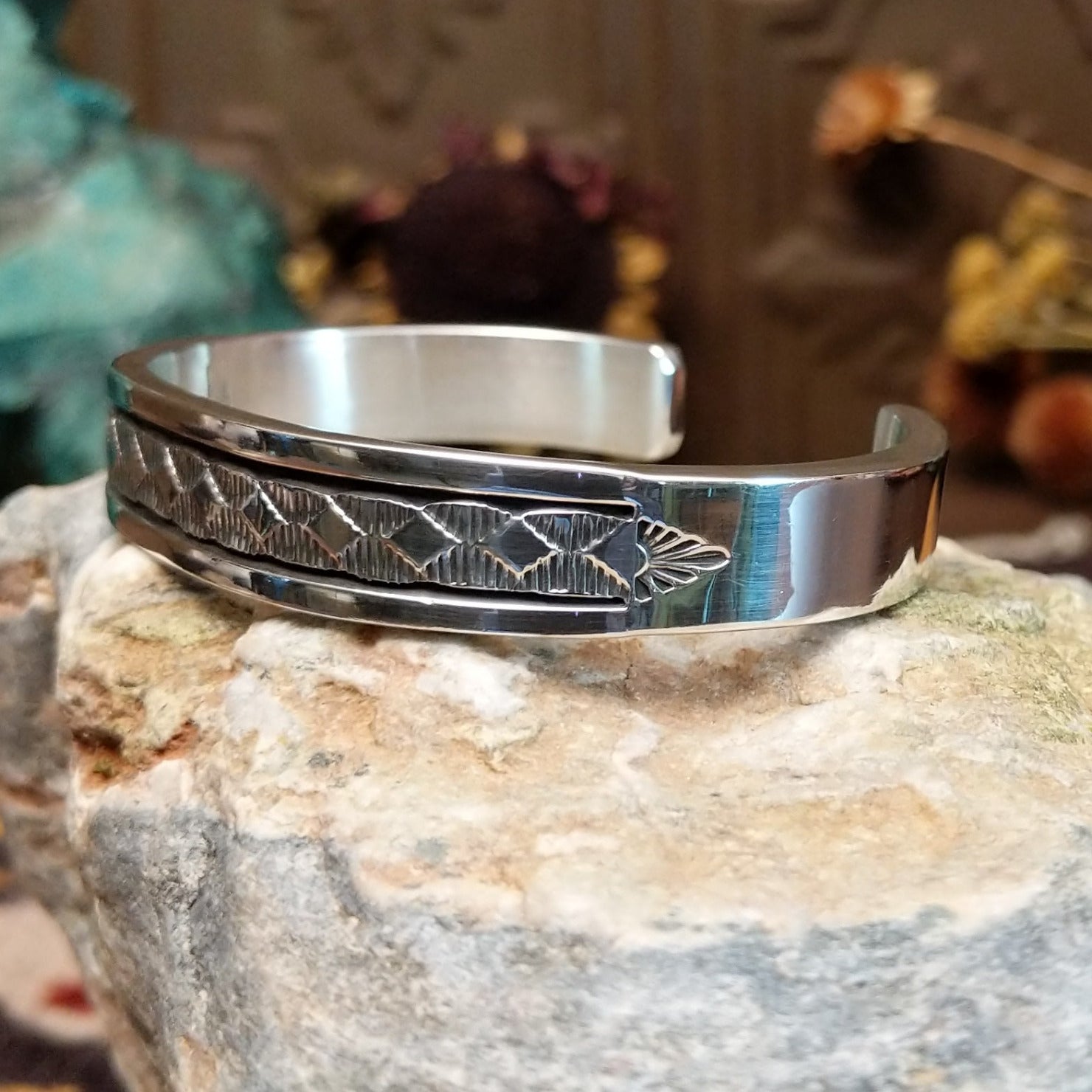 Sterling silver cuff bracelet with geometric stamped details and polished borders.