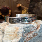 Sterling silver cuff bracelet with geometric stamped details and polished borders.