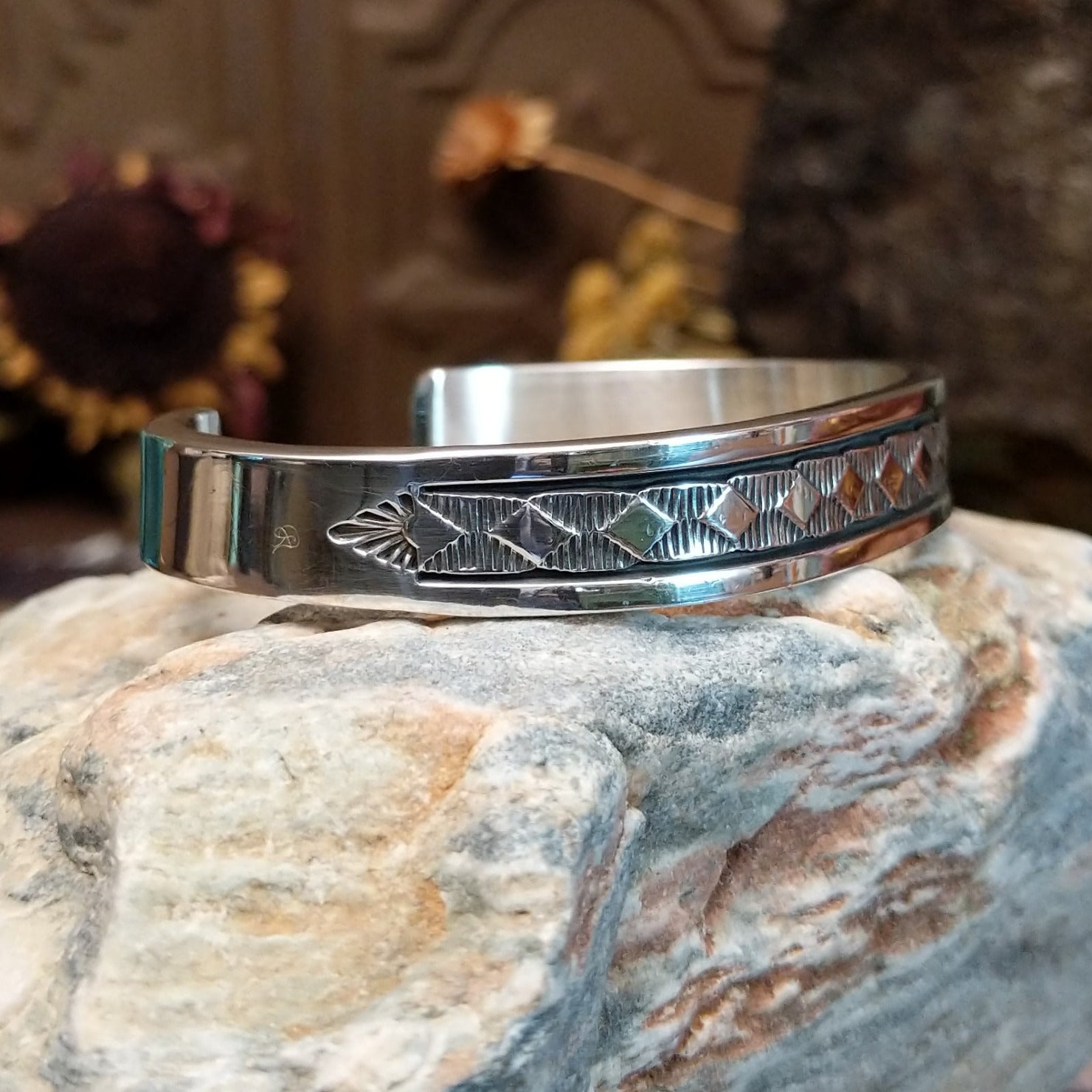 Sterling silver cuff bracelet with geometric stamped details and polished borders.