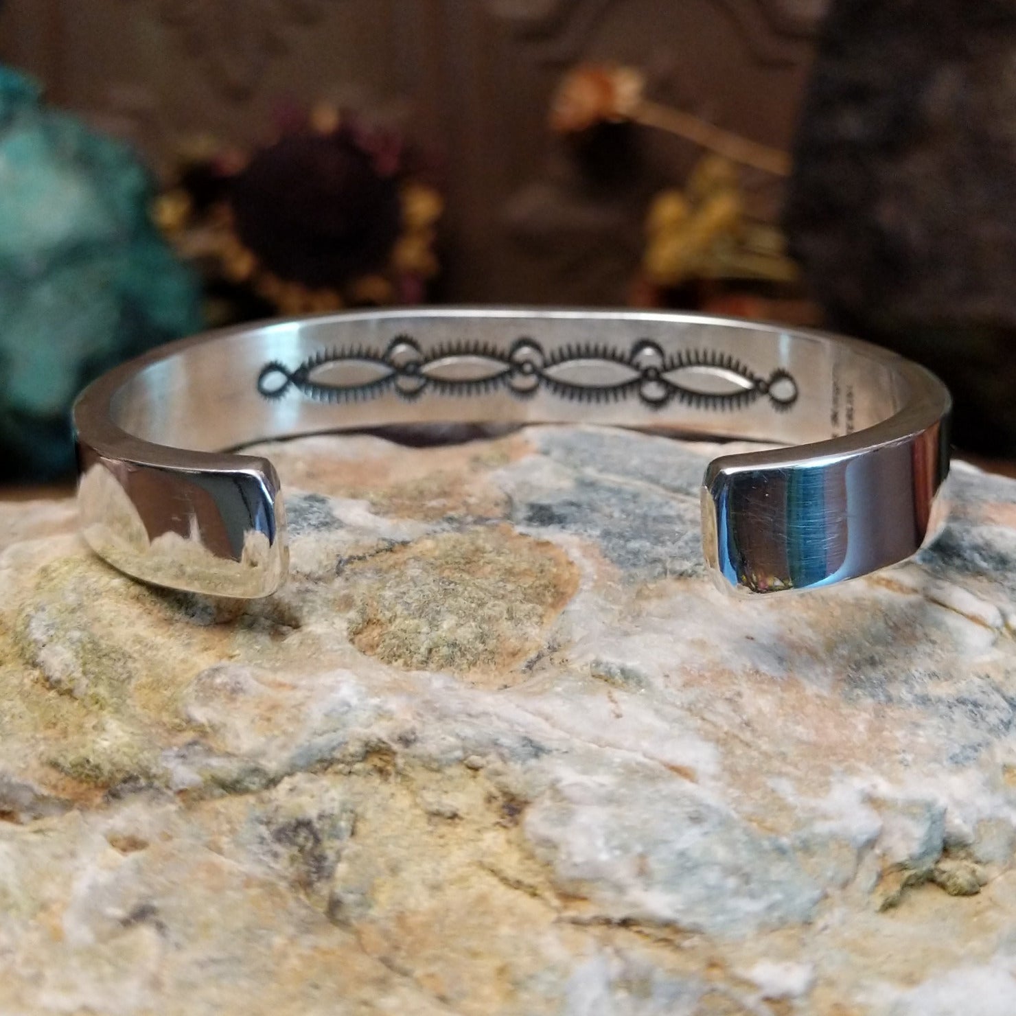 Sterling silver cuff bracelet with geometric stamped details and polished borders.