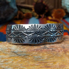 Wide silver cuff by Charlene Robert Little with three rows of repeating fan and geometric stampwork.