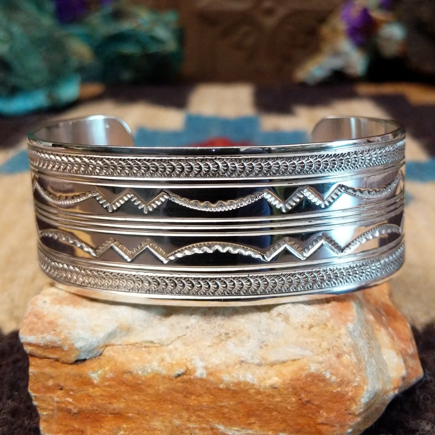 Stamped sterling silver cuff by Gilbert Begay, featuring intricate hand-stamped patterns, a polished finish, and handcrafted Southwestern-inspired design.