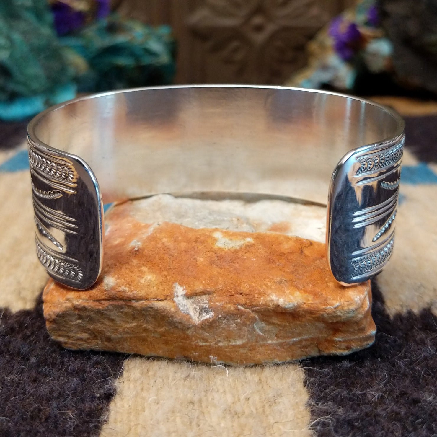 Stamped sterling silver cuff by Gilbert Begay, featuring intricate hand-stamped patterns, a polished finish, and handcrafted Southwestern-inspired design.  Underside view.
