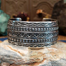 Wide sterling silver cuff bracelet with hand-stamped geometric and crescent motifs.