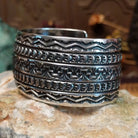 Wide sterling silver cuff bracelet with hand-stamped geometric and crescent motifs.