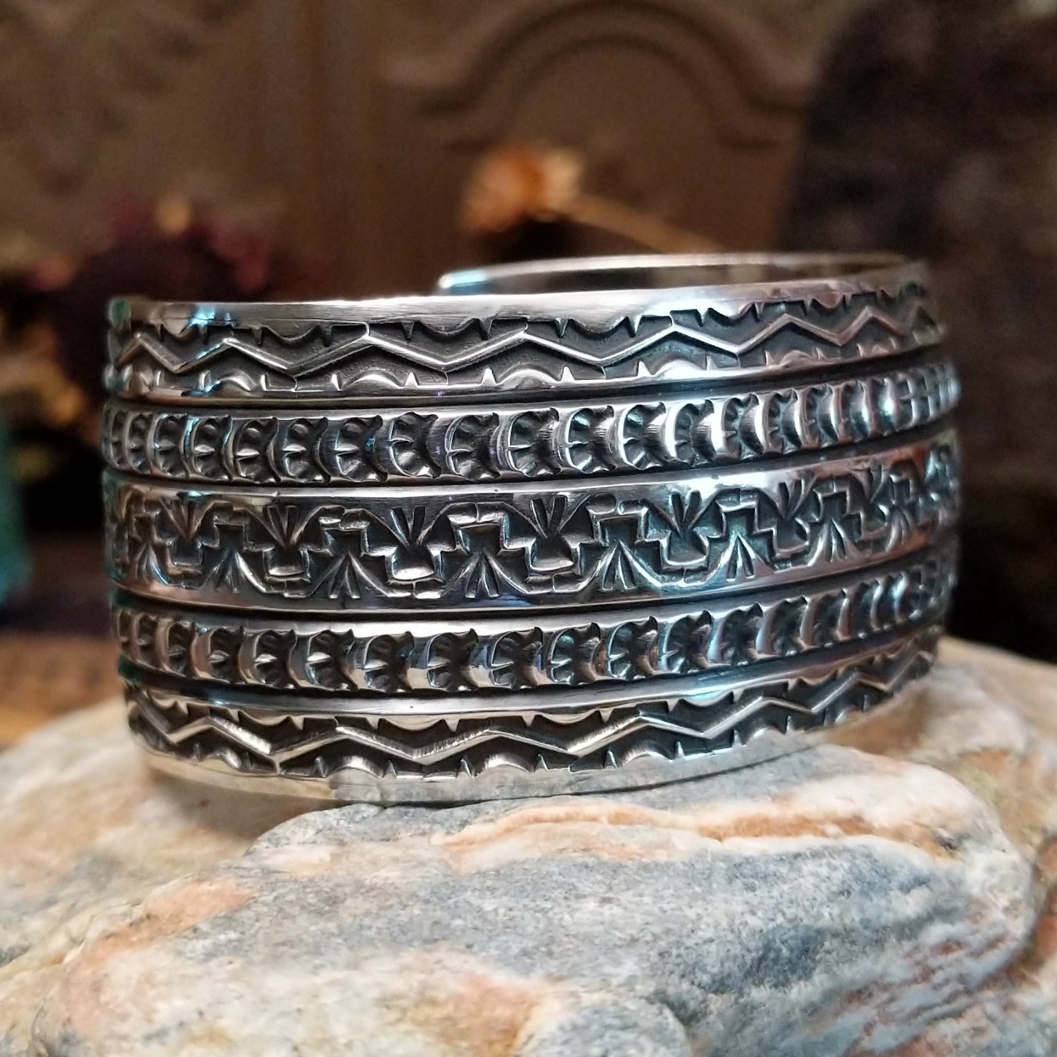 Wide sterling silver cuff bracelet with hand-stamped geometric and crescent motifs.