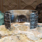 Wide sterling silver cuff bracelet with hand-stamped geometric and crescent motifs.
