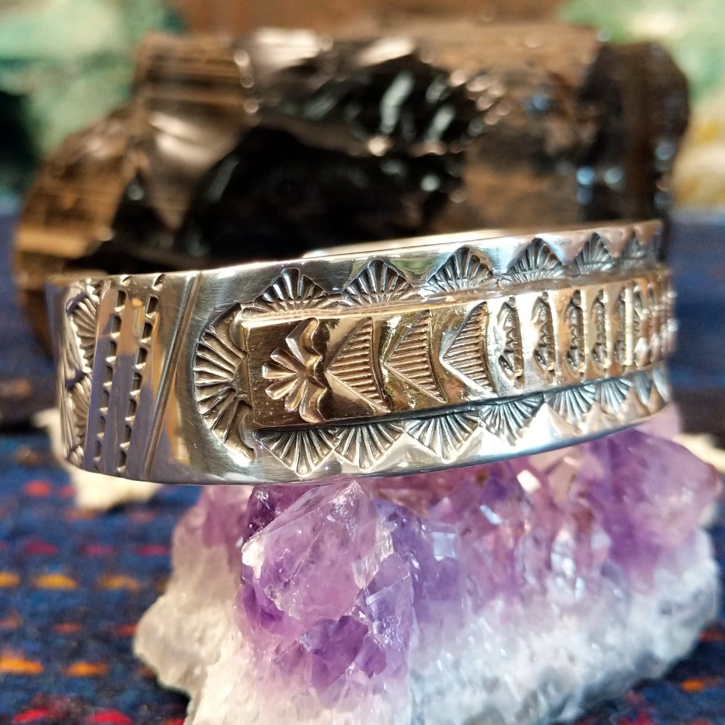 The side features stamped silver and gold cuff with geometric patterns.