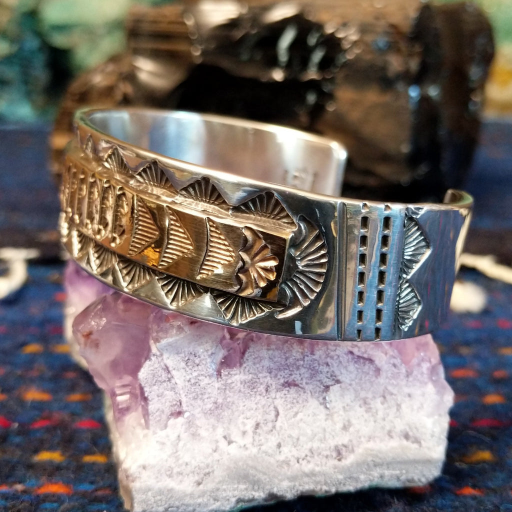 The side features stamped silver and gold cuff with geometric patterns.