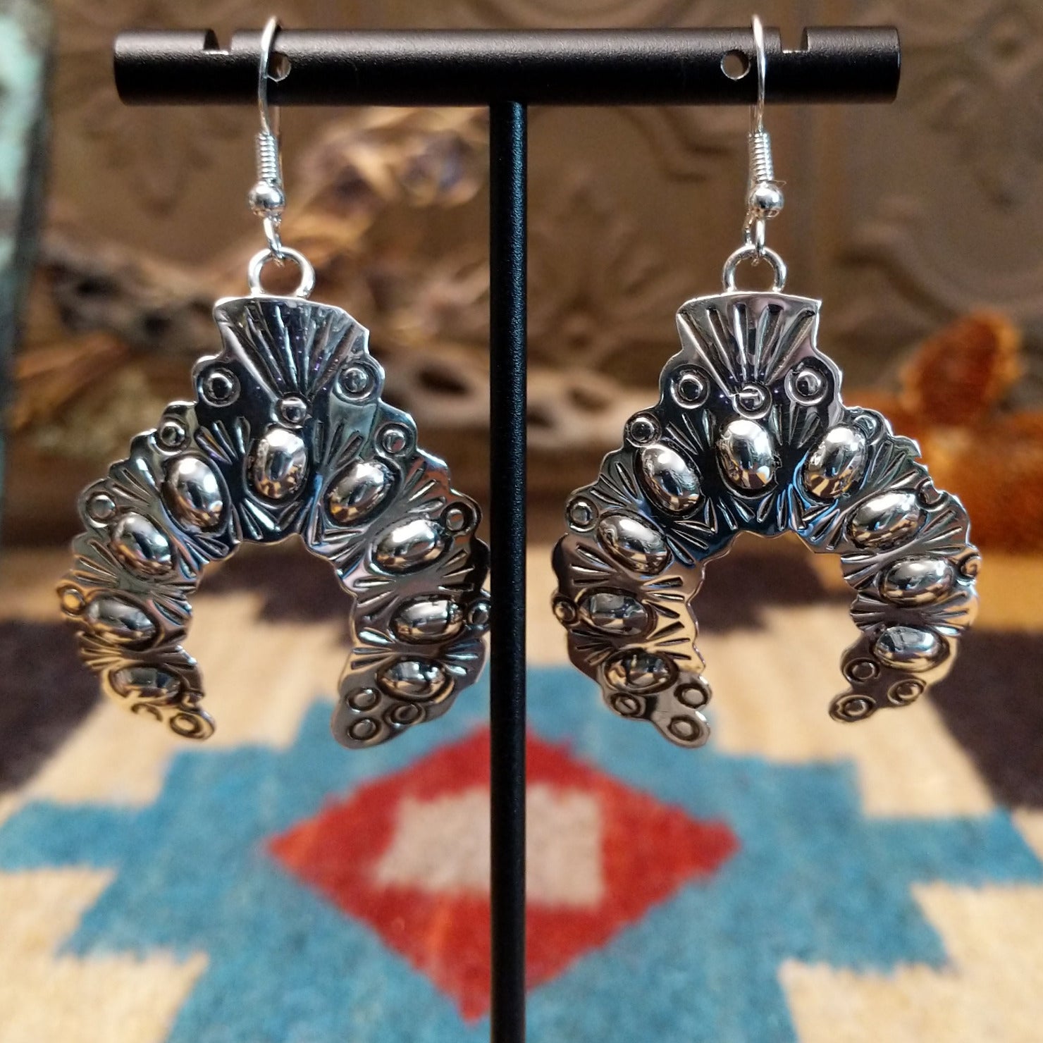 Sterling silver naja earrings with stamping and dotted accents.
