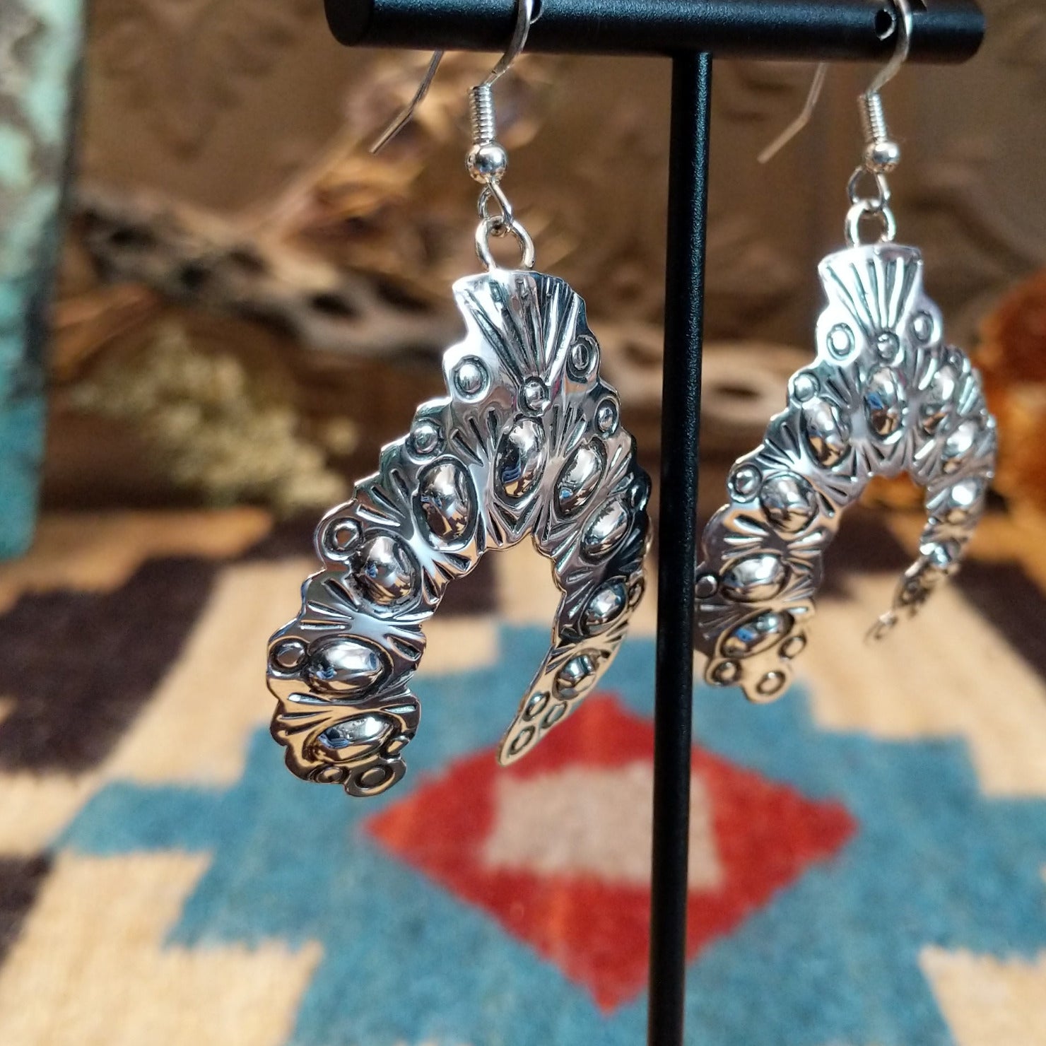 Sterling silver naja earrings with stamping and dotted accents.