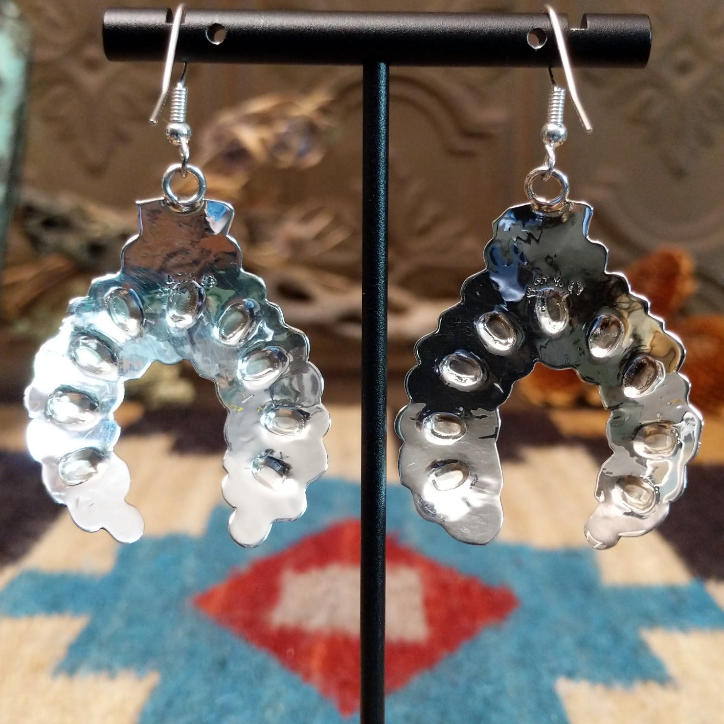 Sterling silver naja earrings with stamping and dotted accents.