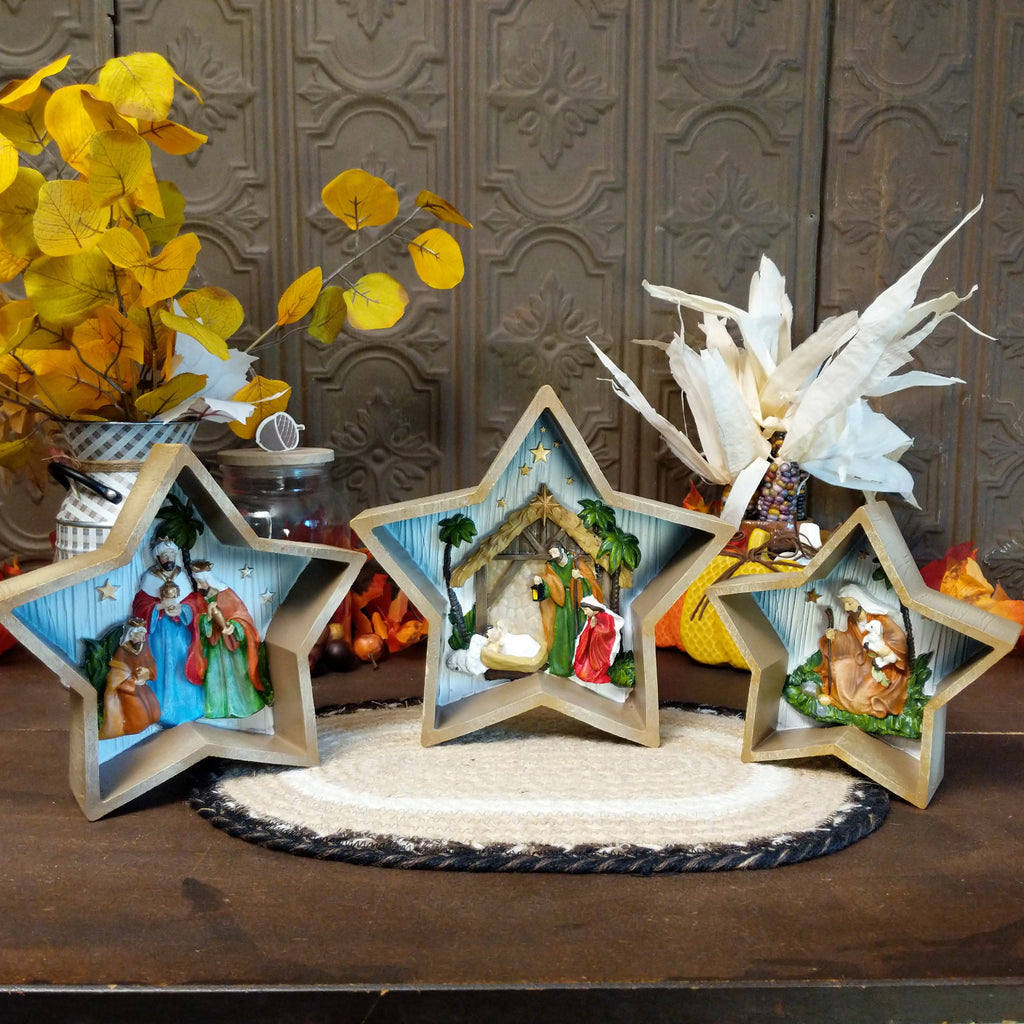 Three stars depicting clay figures of the traditional nativity scene that is painted vibrantly.