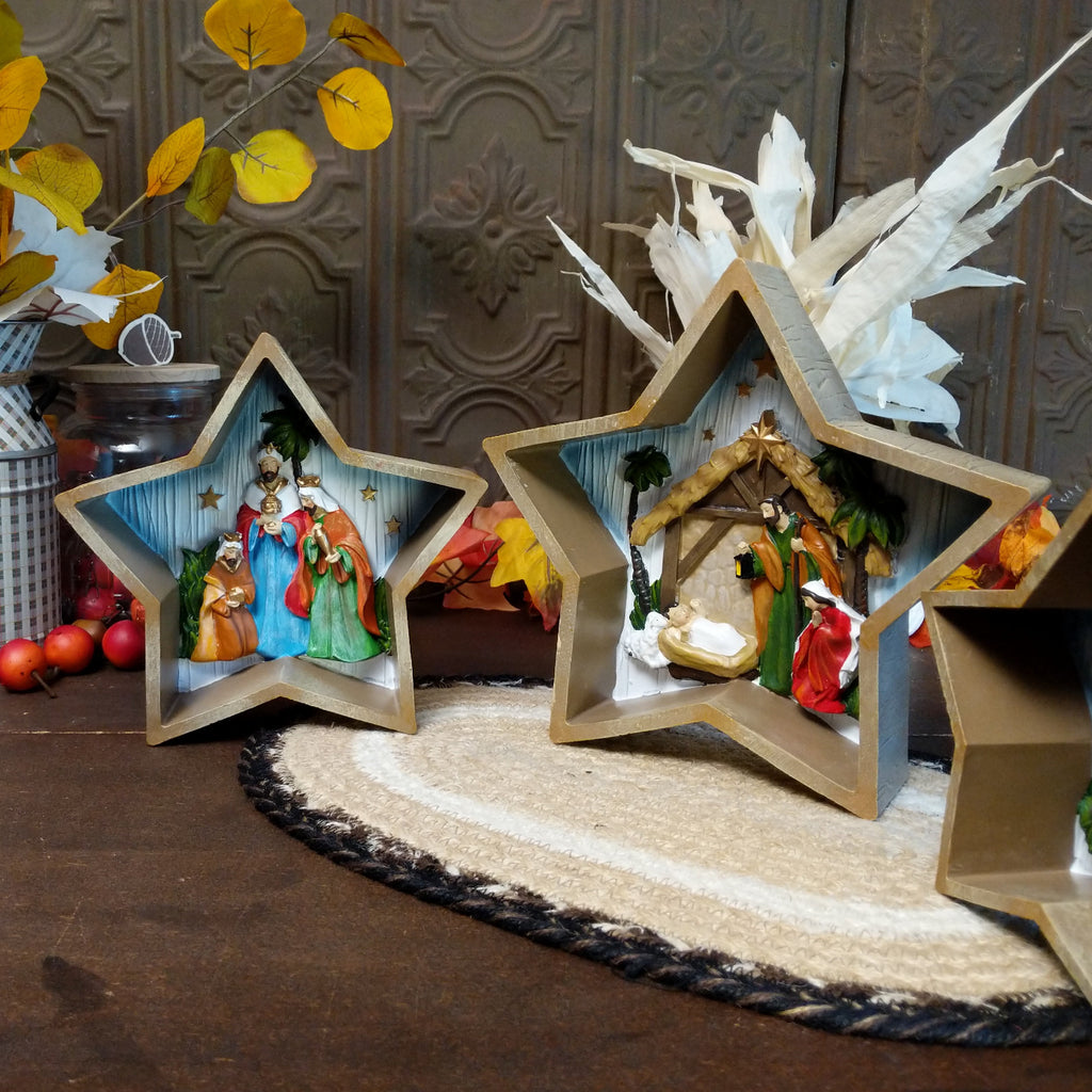 Three stars depicting clay figures of the traditional nativity scene that is painted vibrantly.
