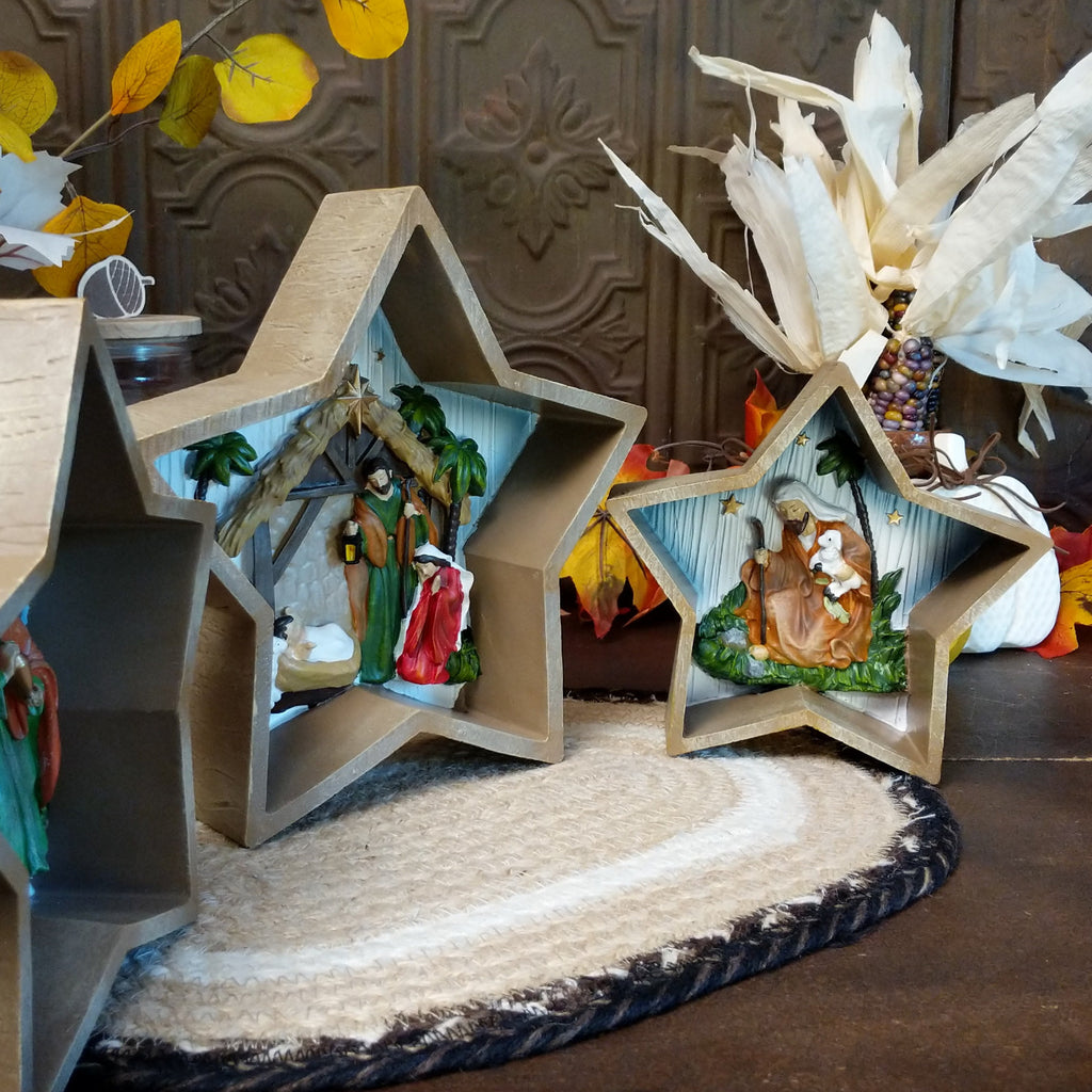 Three stars depicting clay figures of the traditional nativity scene that is painted vibrantly.