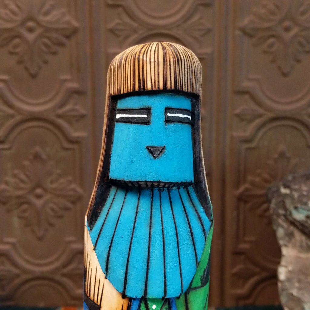 A close-up of the carved, blue face of the piece.