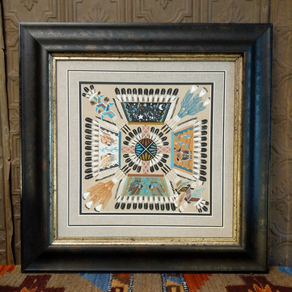 Colorful sands depicting the four directions in Navajo culture set within a wooden frame.