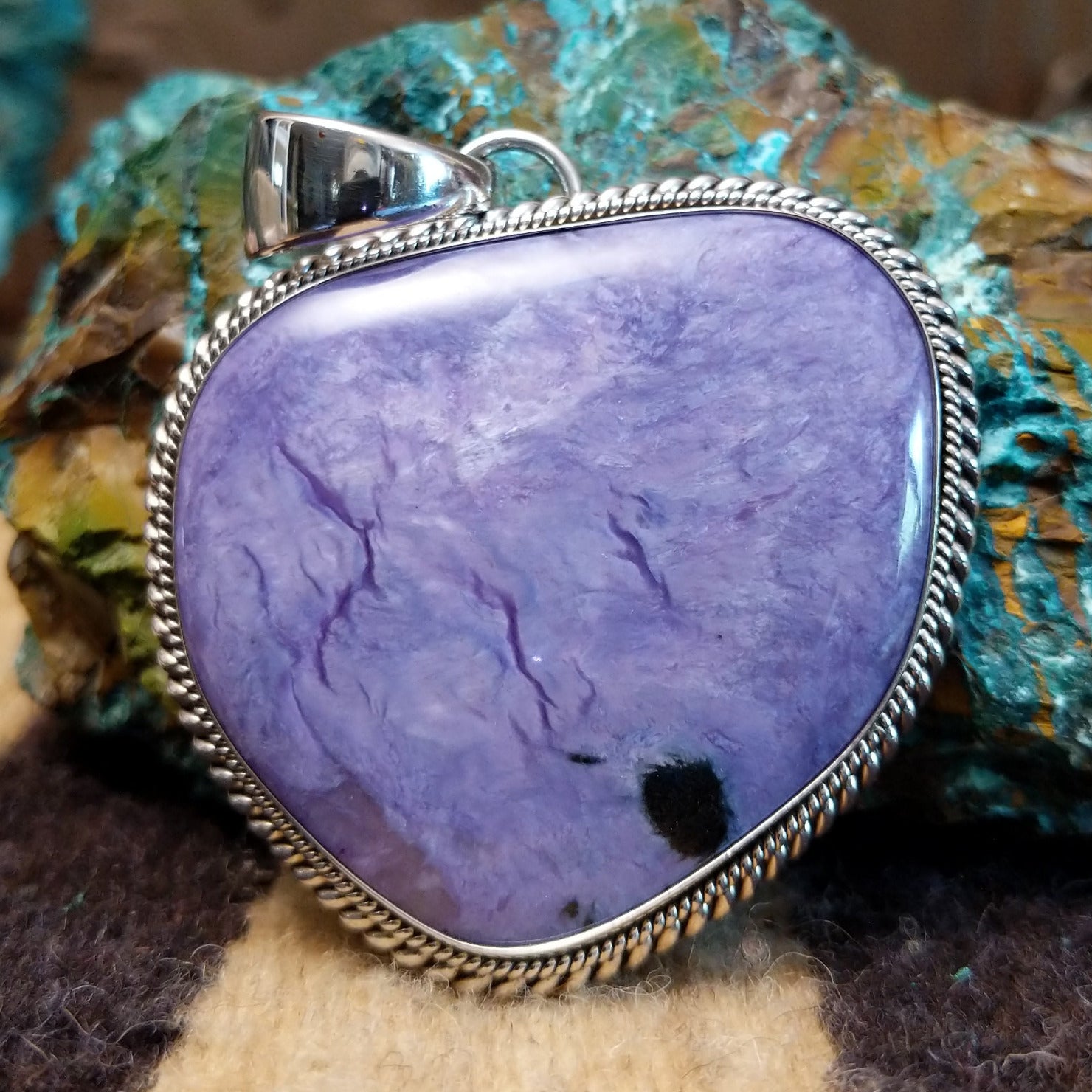 Sterling silver pendant with charoite set in an oblong-shaped bezel.