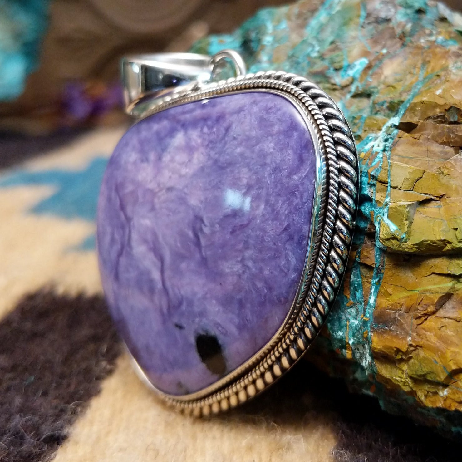Sterling silver pendant with charoite set in an oblong-shaped bezel.