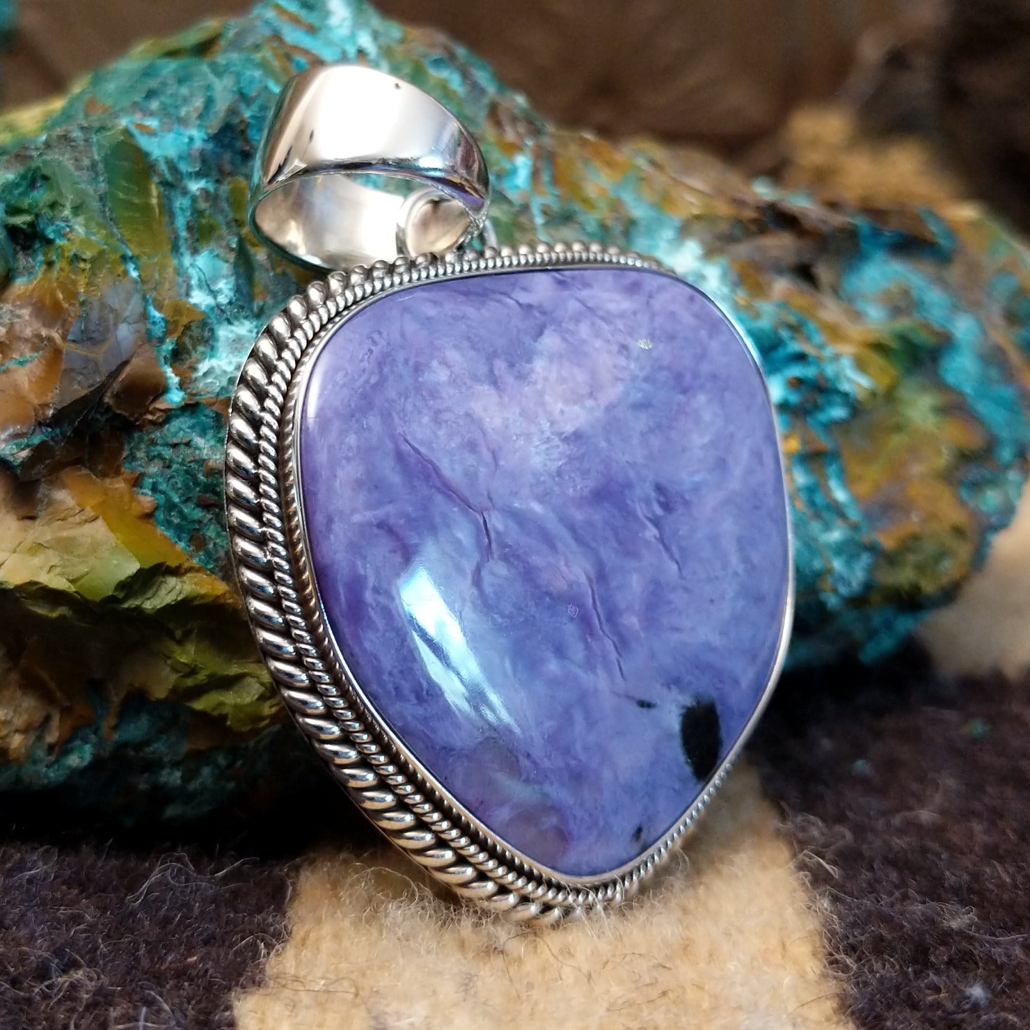 Sterling silver pendant with charoite set in an oblong-shaped bezel.