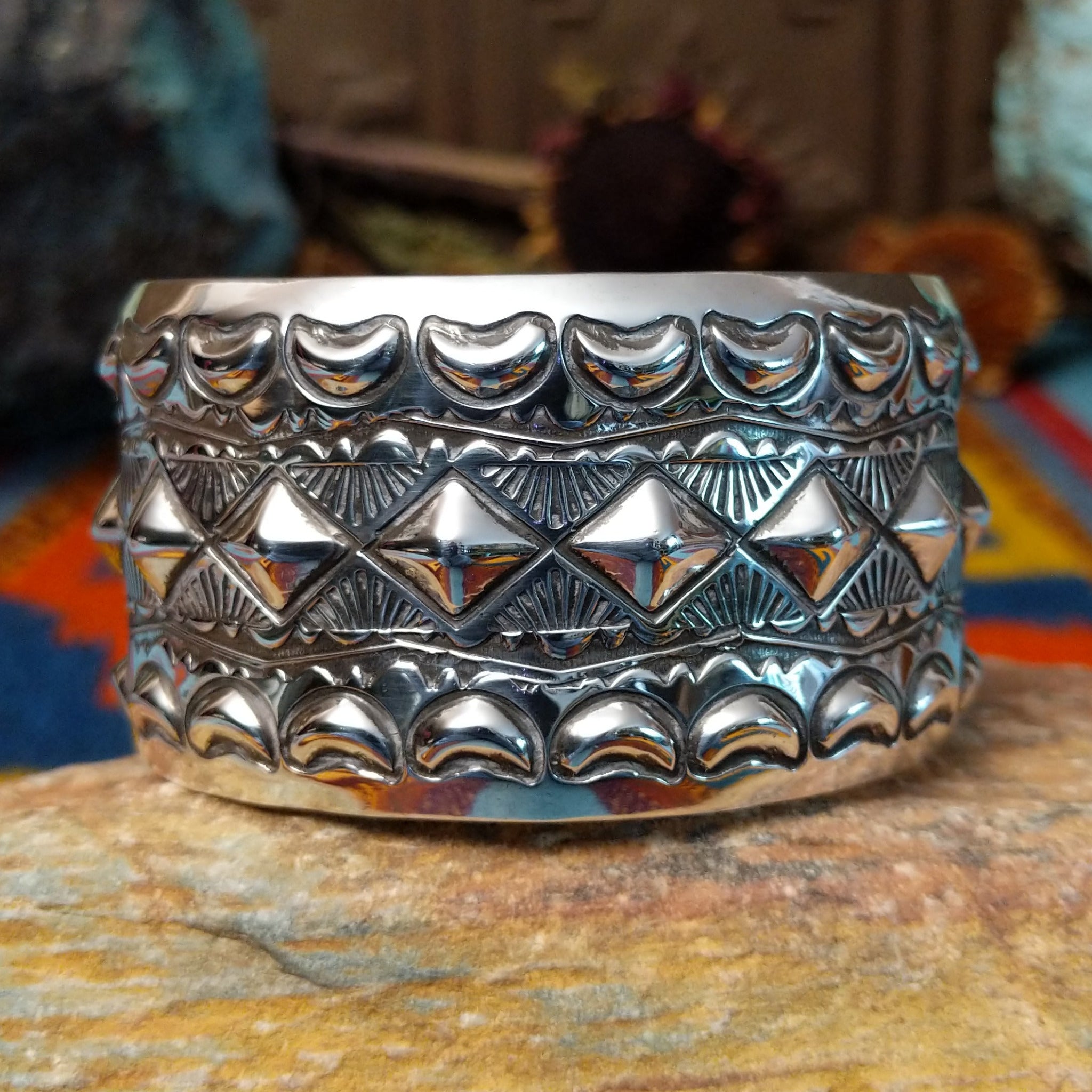 Wide silver cuff by Emerson Bill with raised diamond studs, crescent borders, and geometric stampwork.