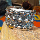 Wide silver cuff by Emerson Bill with raised diamond studs, crescent borders, and geometric stampwork.