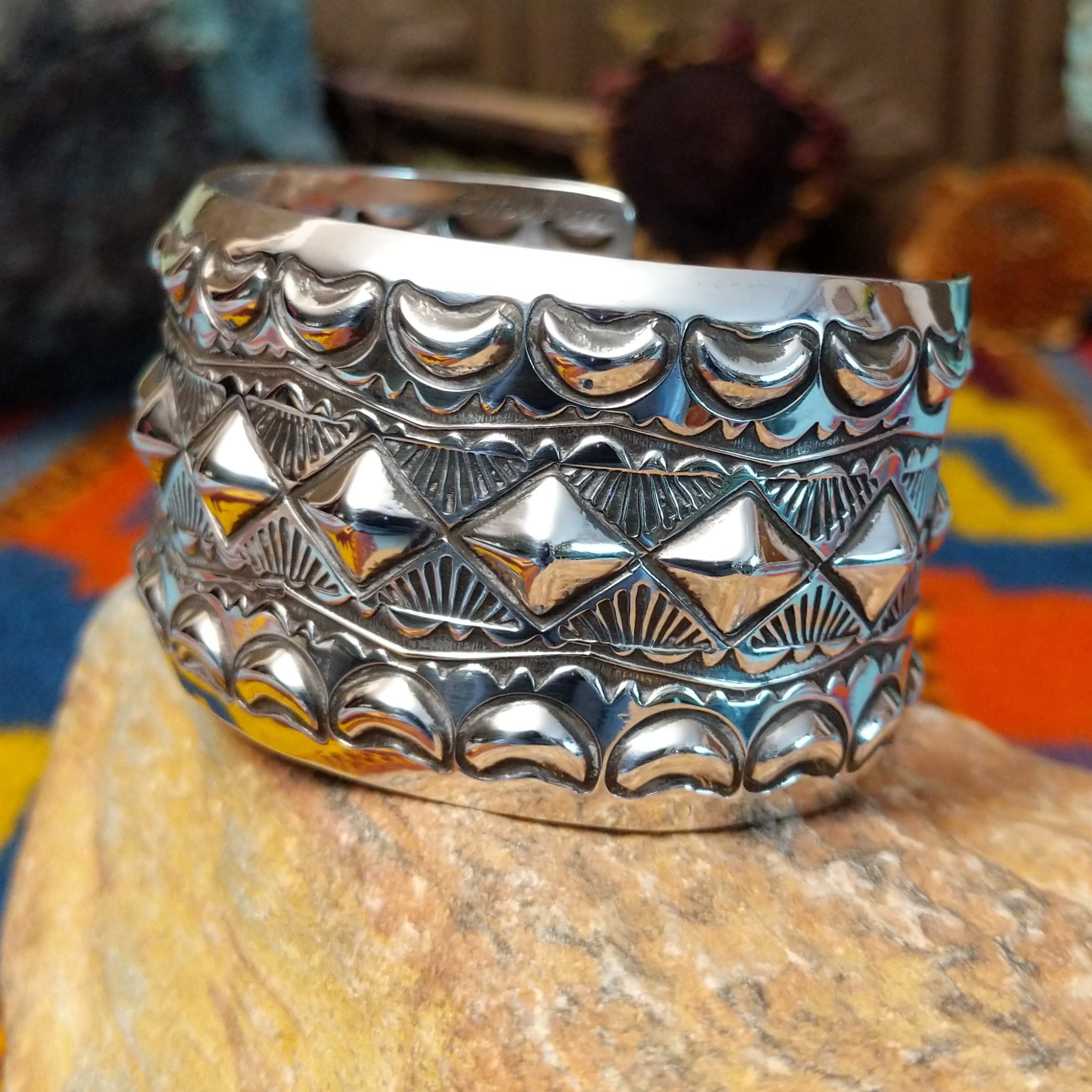 Wide silver cuff by Emerson Bill with raised diamond studs, crescent borders, and geometric stampwork.