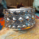 Wide silver cuff by Emerson Bill with raised diamond studs, crescent borders, and geometric stampwork.