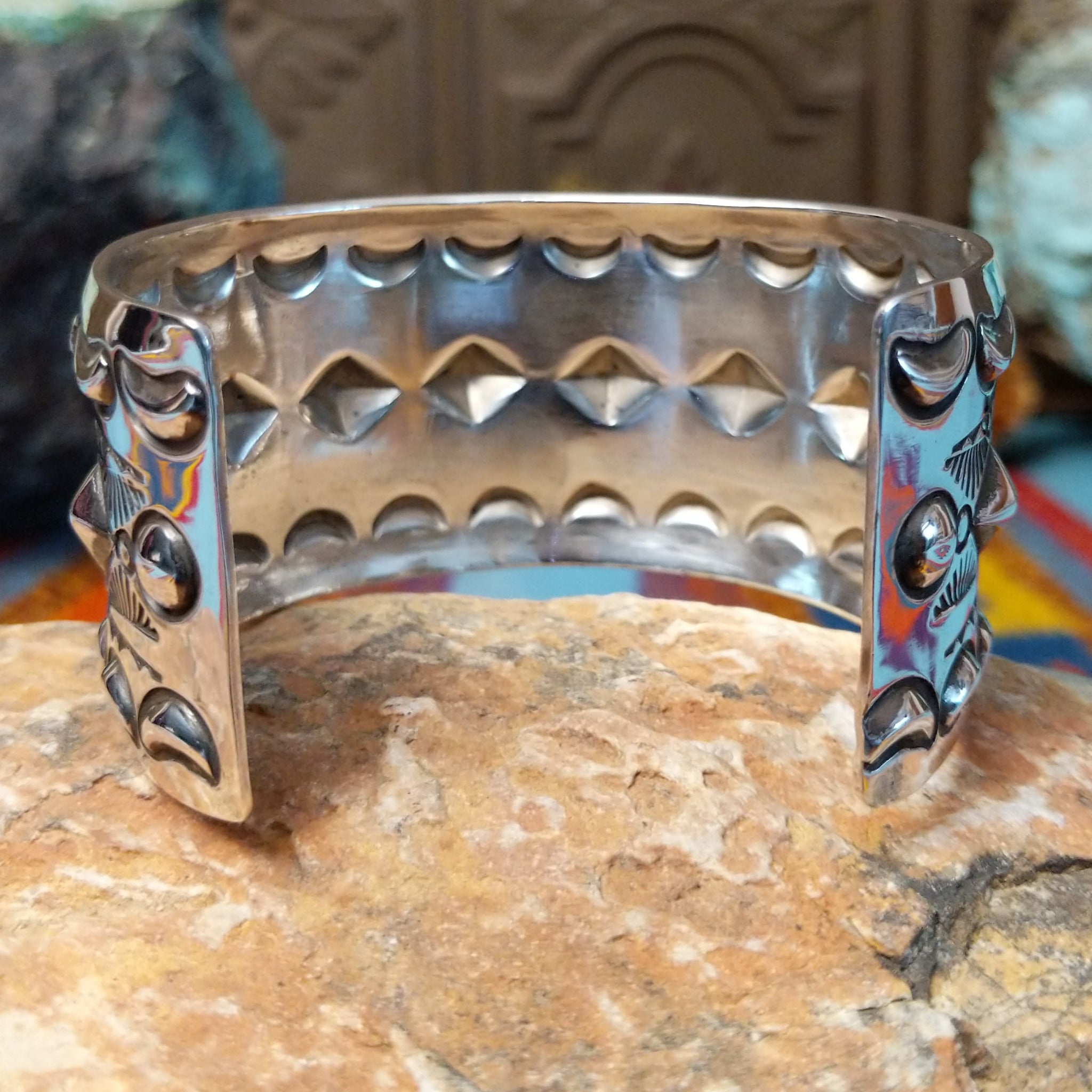 Wide silver cuff by Emerson Bill with raised diamond studs, crescent borders, and geometric stampwork.