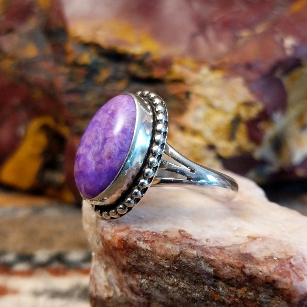 Sugilite framed by dotted accents, raised on the thin, sterling silver band.