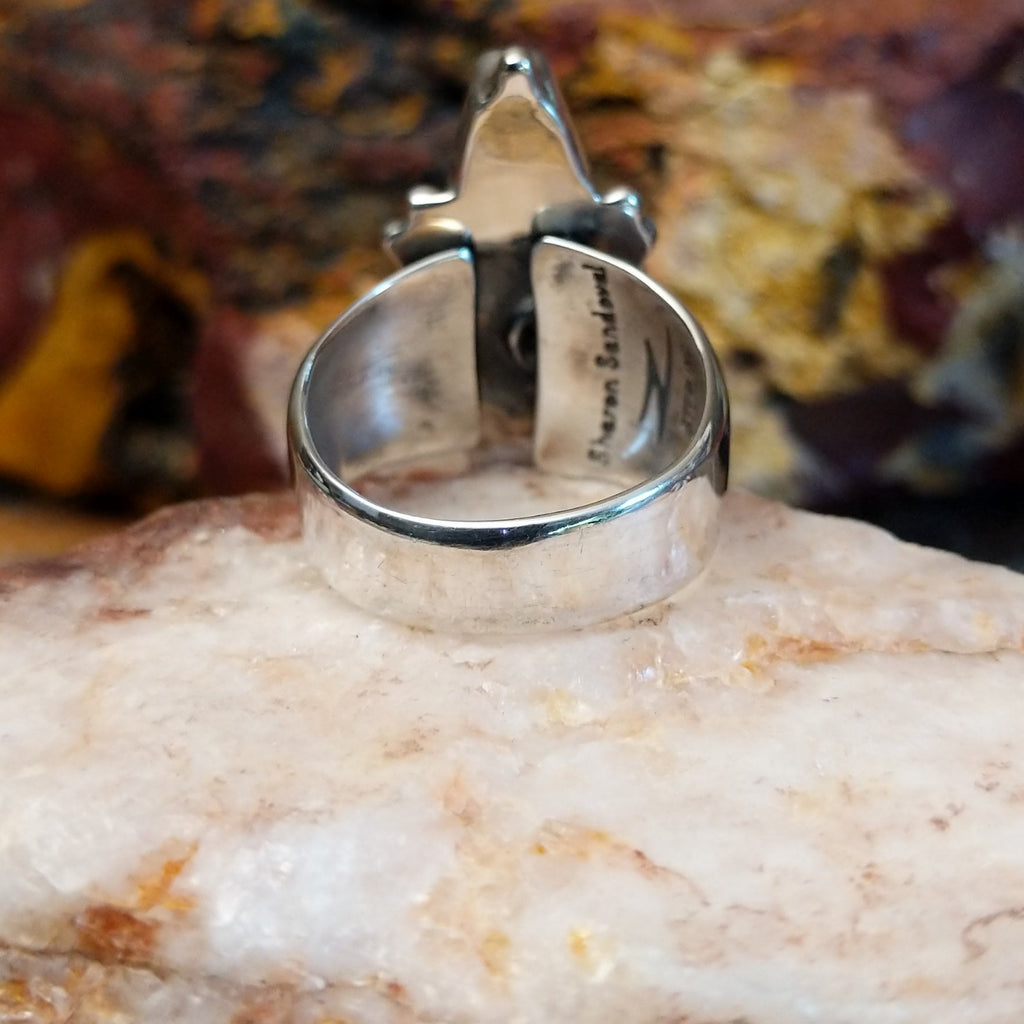 Triangular sugilite stone set within a sterling silver ring.