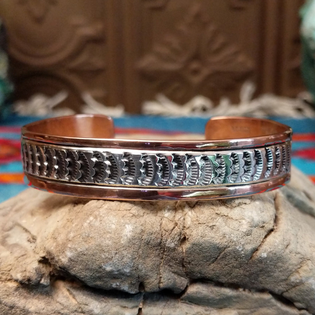 Copper and sterling silver cuff with sun stamps and polished finish.