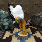 Navajo-made Sunface kachina doll by M. C. with circular multicolored mask, white feather halo, and yellow garments.