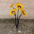 A metal sunflower bouquet with bright yellow petals and copper centers on black-green stems.