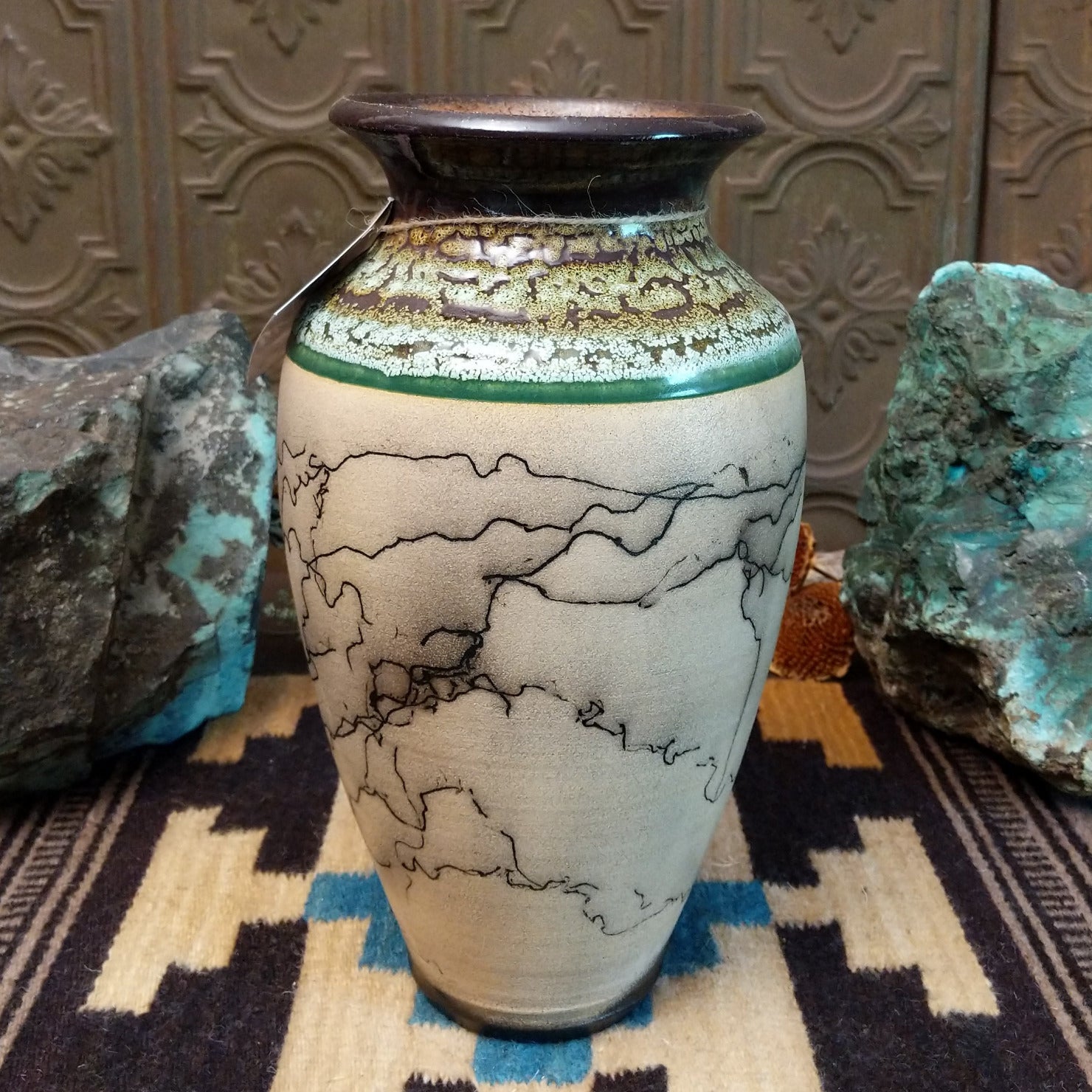 Ceramic pottery piece with horsehair fired onto the surface, and crackled moss colored glaze on the top half of the pot.