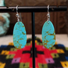 Tan Matrix Turquoise Slab Earrings by Ronald Chavez featuring elongated sky-blue turquoise stones with natural tan and golden-brown matrix, suspended from silver hooks.