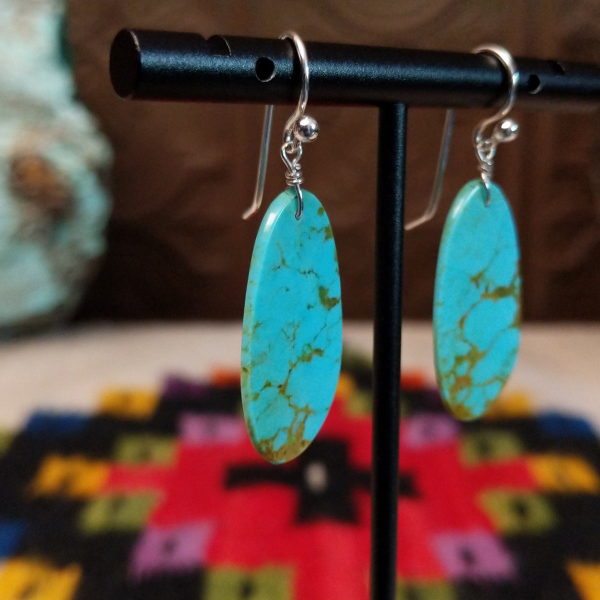 Tan Matrix Turquoise Slab Earrings by Ronald Chavez featuring elongated sky-blue turquoise stones with natural tan and golden-brown matrix, suspended from silver hooks; side view.