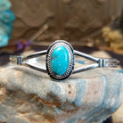 Sterling silver cuff with turquoise set in an oval bezel, framed by twisted rope and incised setting.