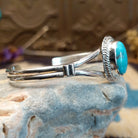 Sterling silver cuff with turquoise set in an oval bezel, framed by twisted rope and incised setting.