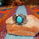 Tiered Turquoise Ring by Augustine Largo featuring an oval blue turquoise cabochon in a serrated bezel, surrounded by layered, symmetrical silverwork with radiating stamped details.