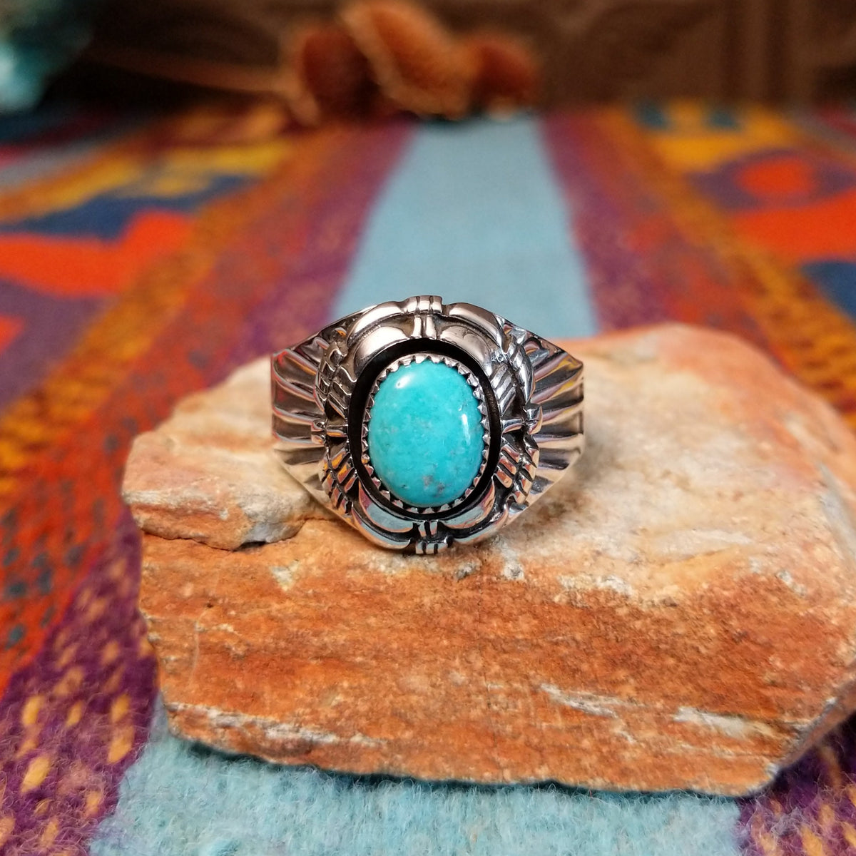Tiered Turquoise Ring by Augustine Largo featuring an oval blue turquoise cabochon in a serrated bezel, surrounded by layered, symmetrical silverwork with radiating stamped details.